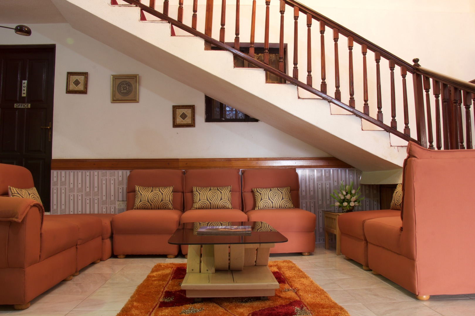 Elegant hotel lobby with wooden staircase and terracotta seating