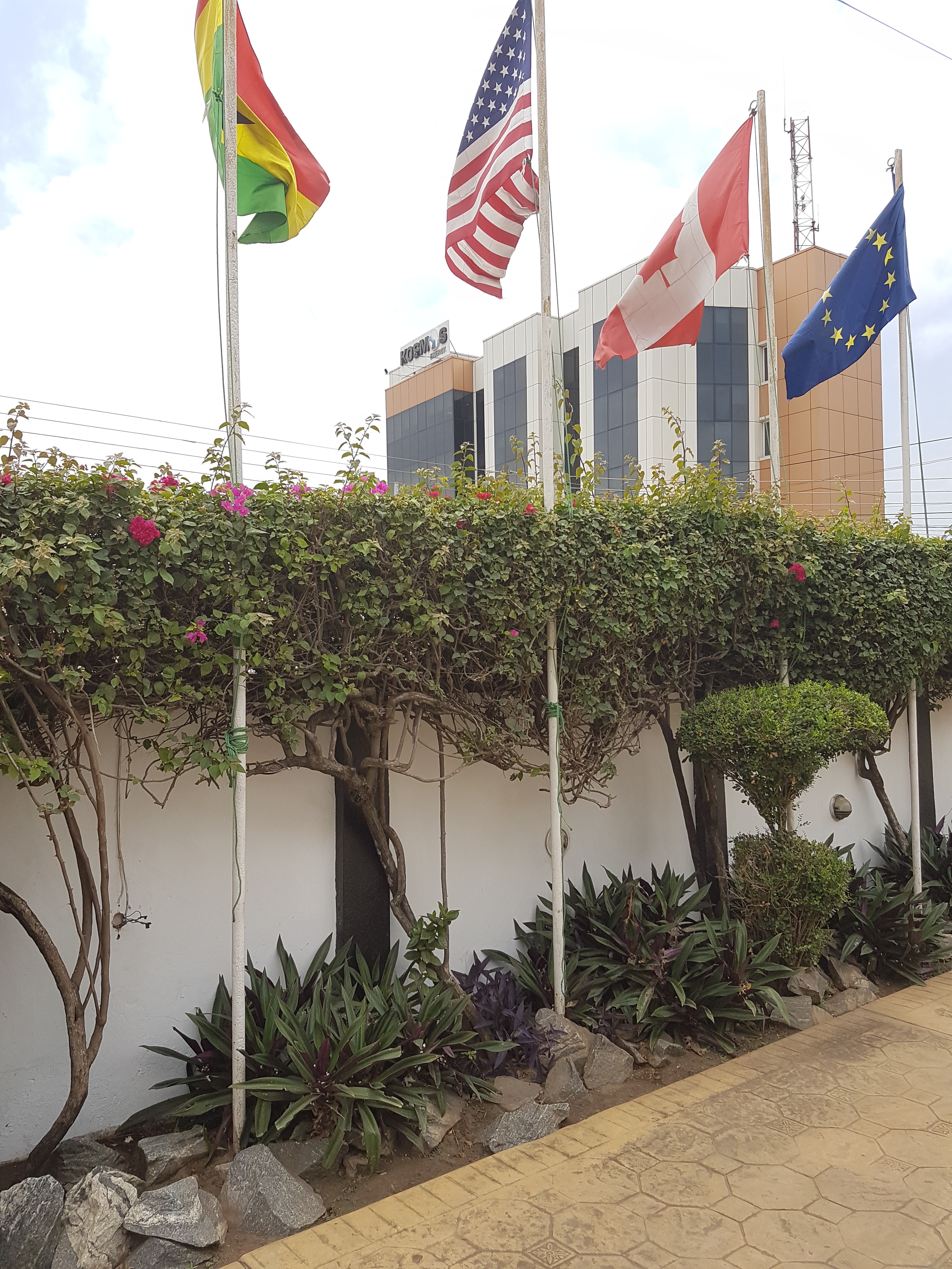 West Airport hotel exterior with international flags and lush garden